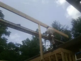 Carpenter setting a ridge beam over a new addition frame — Ice Dam Removal by Roofing Brothers in Cumming