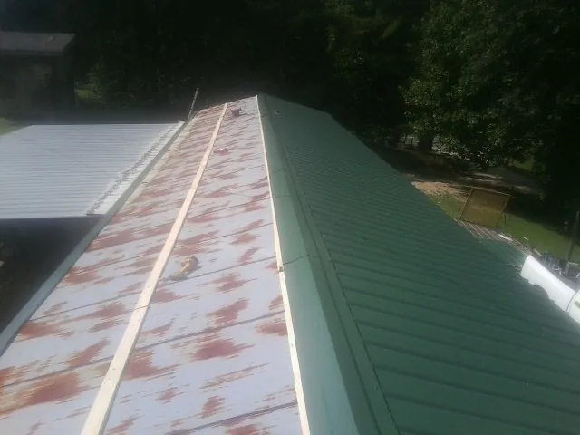 Old rusted panels beside newly installed green metal roofing — Wind Damage Roof Repair by Roofing Brothers in Cumming