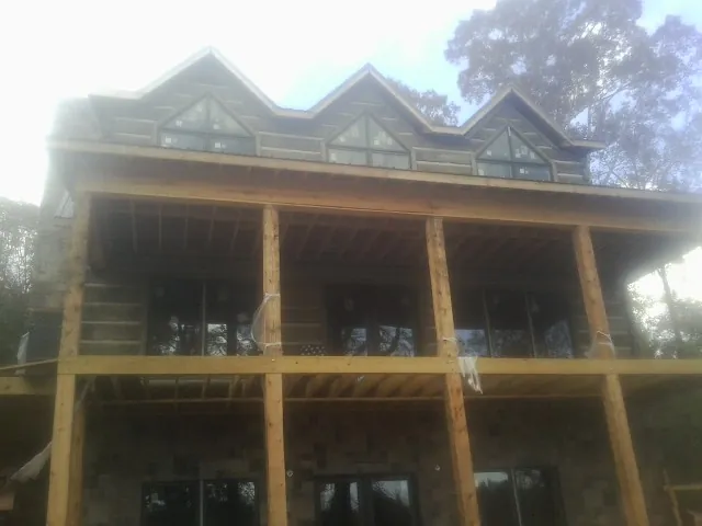 Dormers and porch framing on a large log home under construction — Roof Coating work by our crew in Cumming