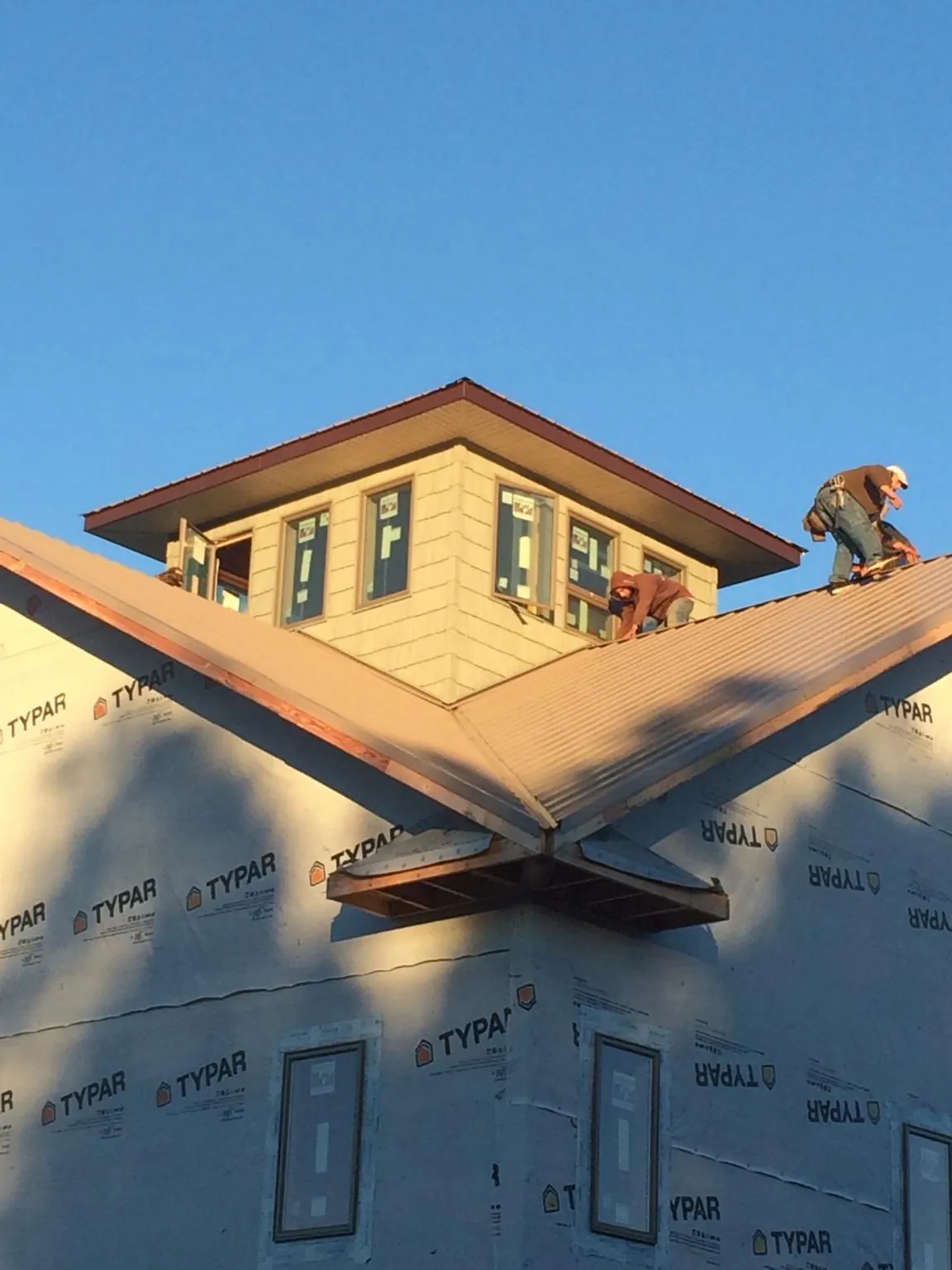 Roofers working around a rooftop cupola on a new metal roof at sunset — Roof Waterproofing in Cumming by Roofing Brothers
